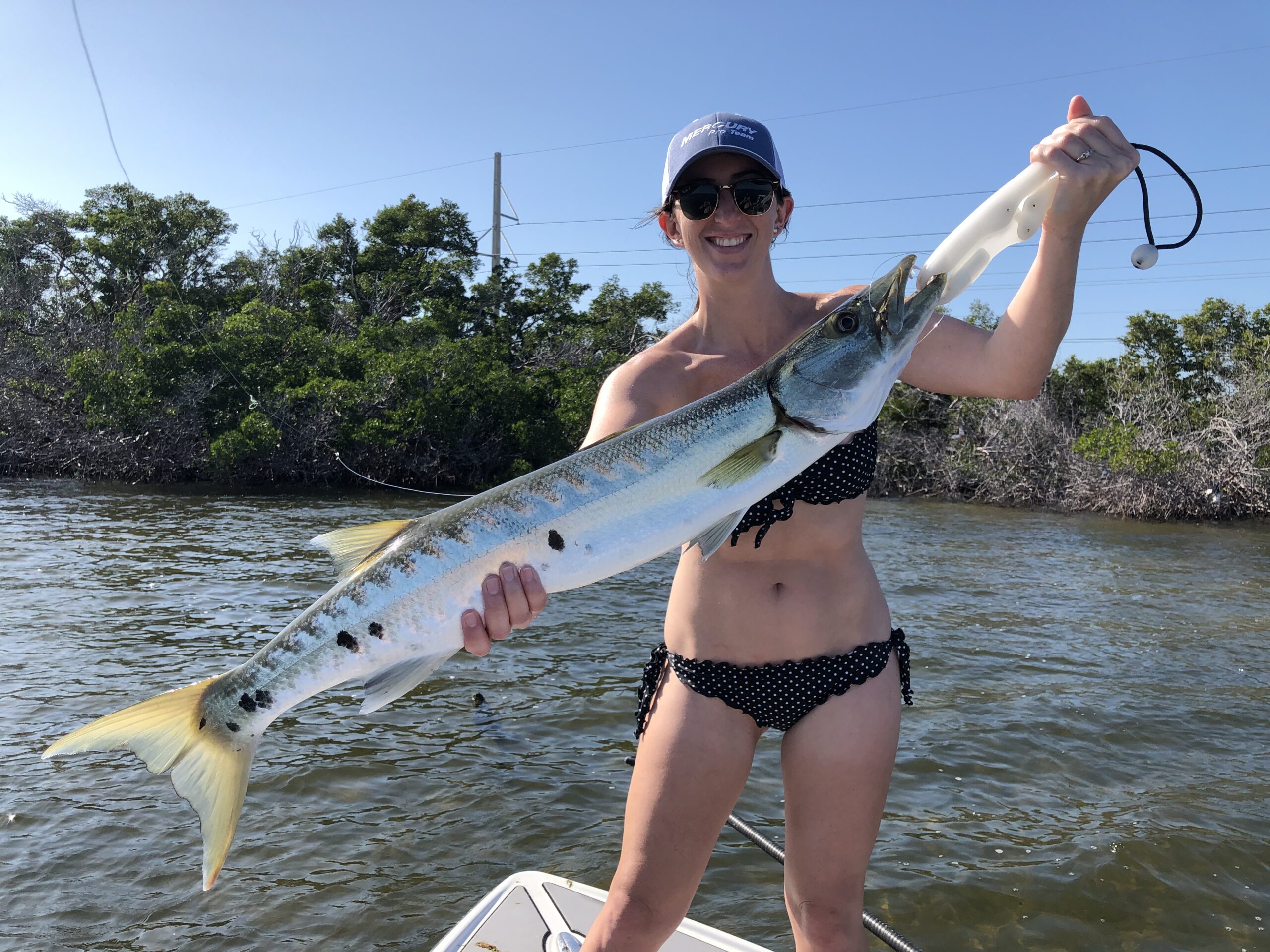 Smiling woman holding caught Barracuda - Opens photo gallery