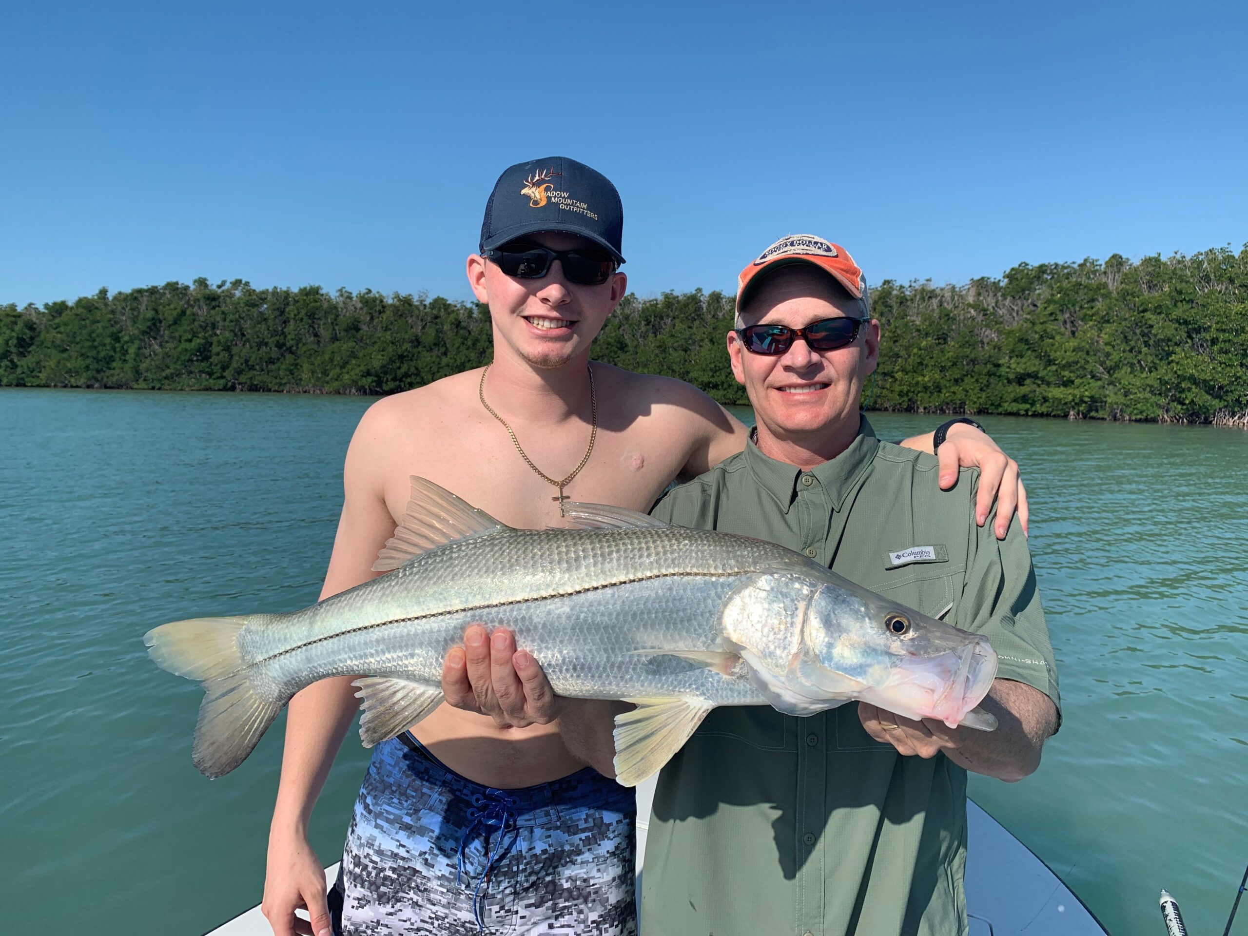 Happy father and son holding a caught Snook. Opens a photo gallery.