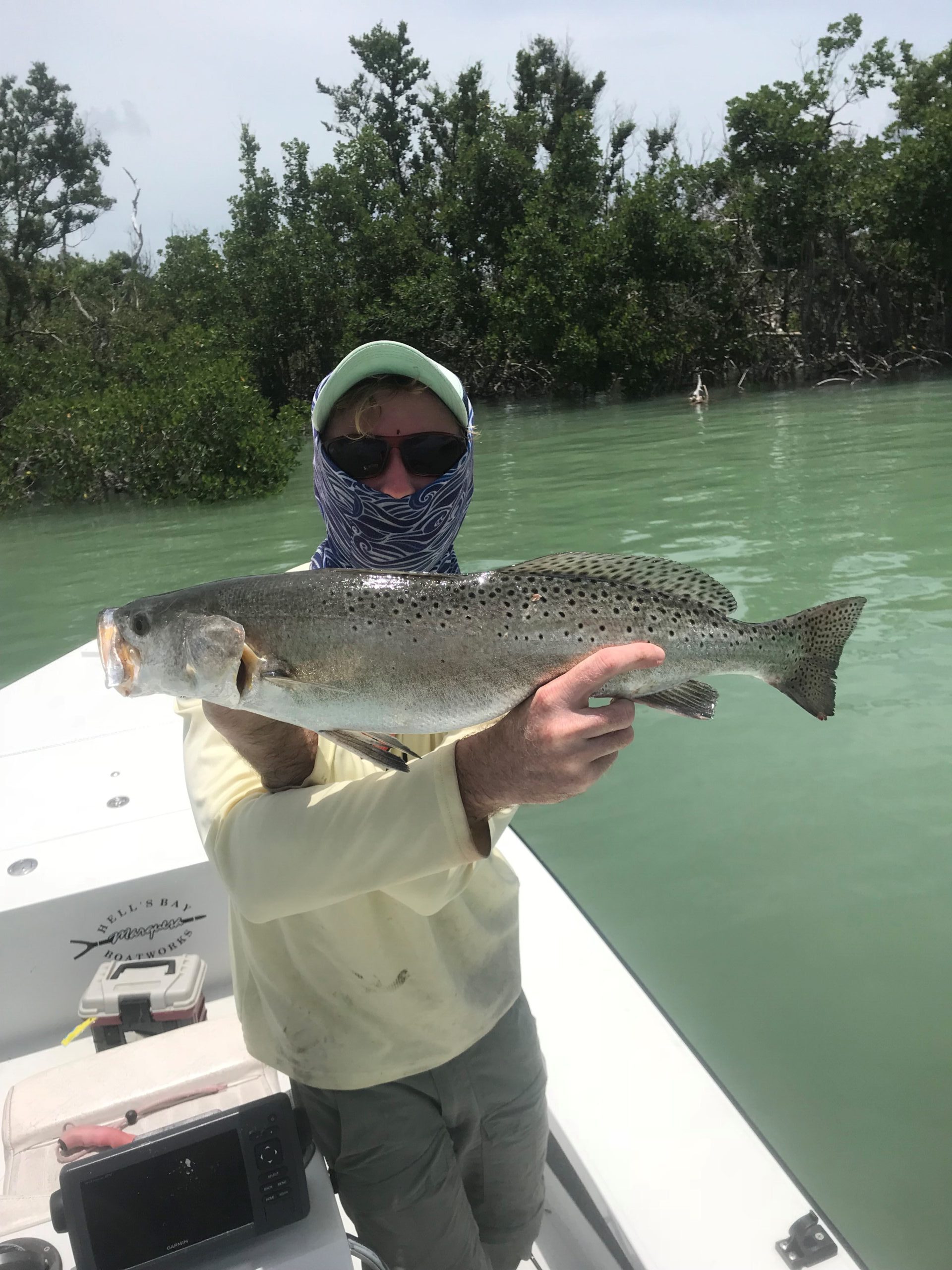 Masked man holding a big Sea Trout. Opens a photo gallery.
